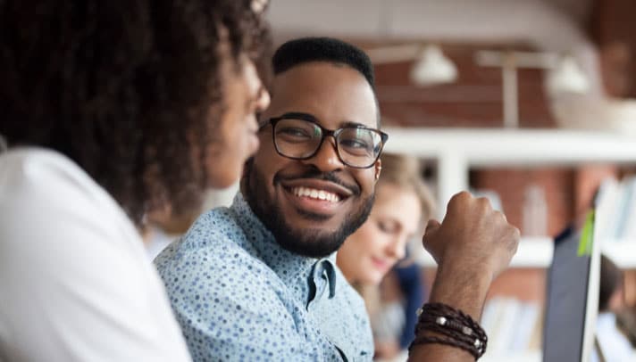 a young person on the travel sales team smiles at a colleague